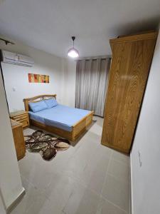 een slaapkamer met een bed en een houten kast bij Coronado North Coast Chalet Sea view for Families Only in El Dab‘a