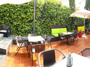 a patio with tables and chairs and a green hedge at Ibis Madrid Fuenlabrada in Fuenlabrada
