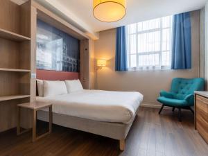ein Hotelzimmer mit einem Bett und einem blauen Stuhl in der Unterkunft Aparthotel Adagio Liverpool City Centre in Liverpool