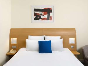 een slaapkamer met een groot bed met een blauw kussen bij Novotel Budapest Danube in Boedapest