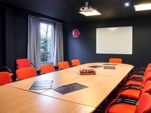 une salle de conférence avec une grande table en bois et des chaises orange dans l'établissement ibis Swansea, à Swansea