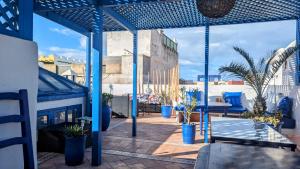 a patio with blue poles and plants on a building at La Maison Du Vent in Essaouira