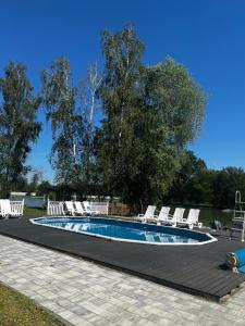 a swimming pool with white chairs and a group at Domki pod Dębami in Mojęcice