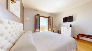 Schlafzimmer mit einem weißen Bett und einem TV in der Unterkunft La Petite Auberge in Tourtour