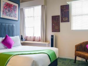 a bedroom with a bed and a window and a chair at Ibis Styles Invercargill in Invercargill