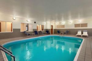 una piscina en una habitación de hotel con sillas y mesas en Wingate by Wyndham Appleton, en Appleton