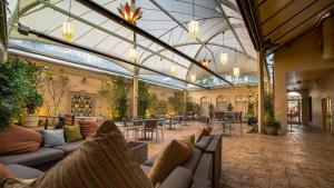 a large conservatory with couches and tables and chairs at Hotel De Anza, a Destination by Hyatt Hotel in San Jose