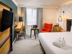 a hotel room with a bed and a television at Mercure Birmingham West Hotel in West Bromwich