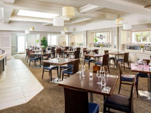 a dining room with tables and chairs and windows at Mercure Birmingham West Hotel in West Bromwich