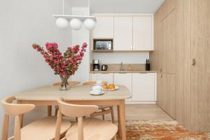 een keuken en eetkamer met een houten tafel en bloemen bij Sun & Beach Apartments Bel Mare with Parking by Renters in Międzyzdroje
