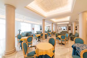 une salle à manger avec des tables, des chaises et des colonnes dans l'établissement Hotel Terme Roma, à Abano Terme