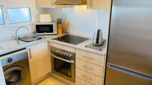 a kitchen with a stainless steel refrigerator and a microwave at Luxury Ground Floor Apartment at Golf Resort Condado de Alhama with Private Garden & Pools in El Romero