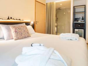 - une chambre avec un grand lit blanc et des serviettes dans l'établissement Mercure Avignon Gare TGV, à Avignon