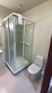 a bathroom with a toilet and a glass shower at Skipalaekur Guesthouse in Egilsstadir