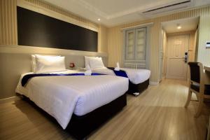 a hotel room with two beds with white sheets at โรงแรมวีวิช V Wish Hotel in Khon Kaen