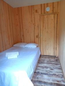Cama en habitación con pared de madera en Vastseliina Metskond Camping en Vahtseliina