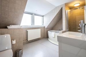 a bathroom with a tub and a sink and a toilet at HOTEL SØMA Ilulissat in Ilulissat +26 photos