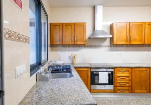 Una cocina con gabinetes de madera y un fregadero. en Maria Benta House, en Ribeira Grande