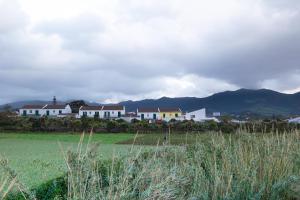 Un grupo de casas en un campo con montañas al fondo. en Maria Benta House, en Ribeira Grande