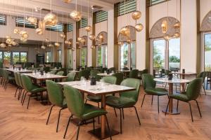 a dining room with tables and green chairs and windows at Wyndham Grand Barbados Sam Lords Castle All Inclusive Resort in Saint Philip