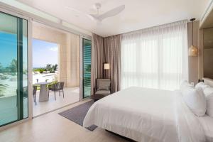 a bedroom with a white bed and a balcony at Wyndham Grand Barbados Sam Lords Castle All Inclusive Resort in Saint Philip