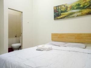 een slaapkamer met een wit bed en een schilderij aan de muur bij RedDoorz near RS Labuang Baji in Balangberu