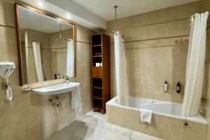 a bathroom with a tub and a sink and a mirror at Cabot Pollensa Park Spa in Port de Pollensa