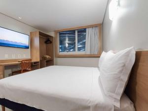 Un dormitorio con una gran cama blanca y una ventana en ibis Styles Goiânia Shopping Estação en Goiânia