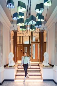 Una mujer caminando por las escaleras en un vestíbulo con una lámpara de araña en Residenz Boutique Suites en Bad Gastein