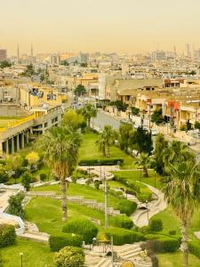 a city with a park with palm trees and buildings at Vote Hotel in Erbil