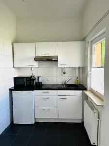 uma cozinha com armários brancos e um piso preto em Bungalow-Wohnung nahe Flughafen Hamburg em Norderstedt