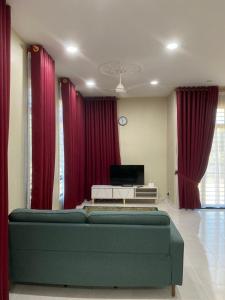 - un salon avec un canapé vert et des rideaux rouges dans l'établissement MJ Homestay Kota Bharu, à Kota Bharu