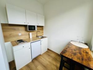 デュースブルクにあるcityprohouse möbliertes wohnenの小さなキッチン(白いキャビネット、木製テーブル付)