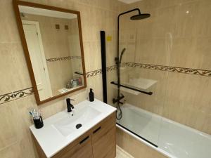 a bathroom with a sink and a tub and a mirror at Bajo con Jardin y Piscina! in Galizano