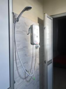 La salle de bains est pourvue d'une douche fixée à un mur. dans l'établissement MJ Homestay Kota Bharu, à Kota Bharu