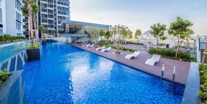 a large swimming pool with white chairs in a building at Lovely Eco Home in Gelang Patah