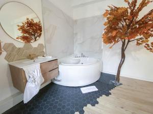a bathroom with a white tub and a tree in it at Hotel Le Céleste in Nice