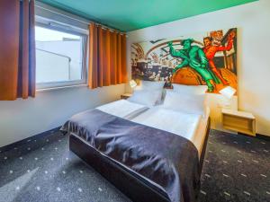 ライプツィヒにあるB＆B ホテル ライプチヒ シティのベッドルーム1室(壁に絵画が描かれたベッド1台付)