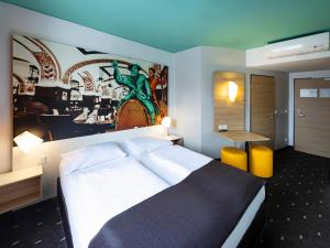 ライプツィヒにあるB＆B ホテル ライプチヒ シティのベッドルーム1室(ベッド1台付)が備わります。壁には絵画が飾られています。