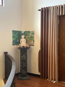 Pokój z zasłoną obok schodów z posągiem w obiekcie Pharo Residence w mieście Anuradhapura