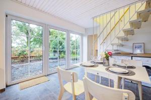 a dining room with a table and chairs and windows at De Strandloper in Westerdeichstrich