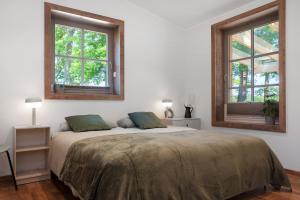 ein weißes Schlafzimmer mit einem Bett und zwei Fenstern in der Unterkunft Eichengeflüster Kranichzimmer in Wagenfeld
