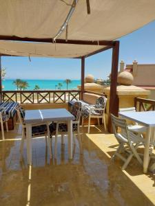 a patio with tables and chairs and a view of the ocean at Lazorde bay Sidi Abd El Rahman لازوردى باى apartment in El Alamein