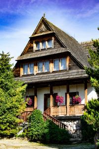 a large wooden house with flowers on the balcony at Pokoje Gościnne Biały Bizon in Rabka-Zdrój