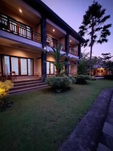 une grande maison avec une pelouse devant elle dans l'établissement Bambu Lokha Guest house, Gianyar Bali, à Ubud