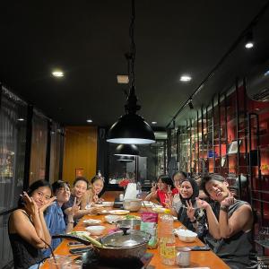 un grupo de personas sentadas en una mesa en Luk Hostel - Digital Nomad friendly, en Bangkok