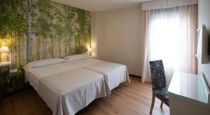 1 dormitorio con 1 cama y una pared con árboles en Hotel Plaza Santa Lucía, en Sevilla