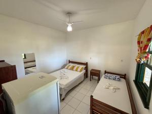 Habitación pequeña con 2 camas y nevera. en Pousada Casarão - Pé na Areia Cumuruxatiba en Cumuruxatiba