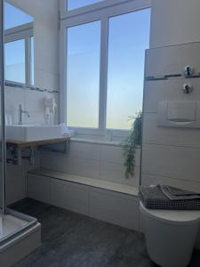 a bathroom with a sink and a toilet and a window at Lexow - Hotel an de Havenkant in Tönning