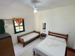 een kleine kamer met 2 bedden en een raam bij Pousada Casarão - Pé na Areia Cumuruxatiba in Cumuruxatiba